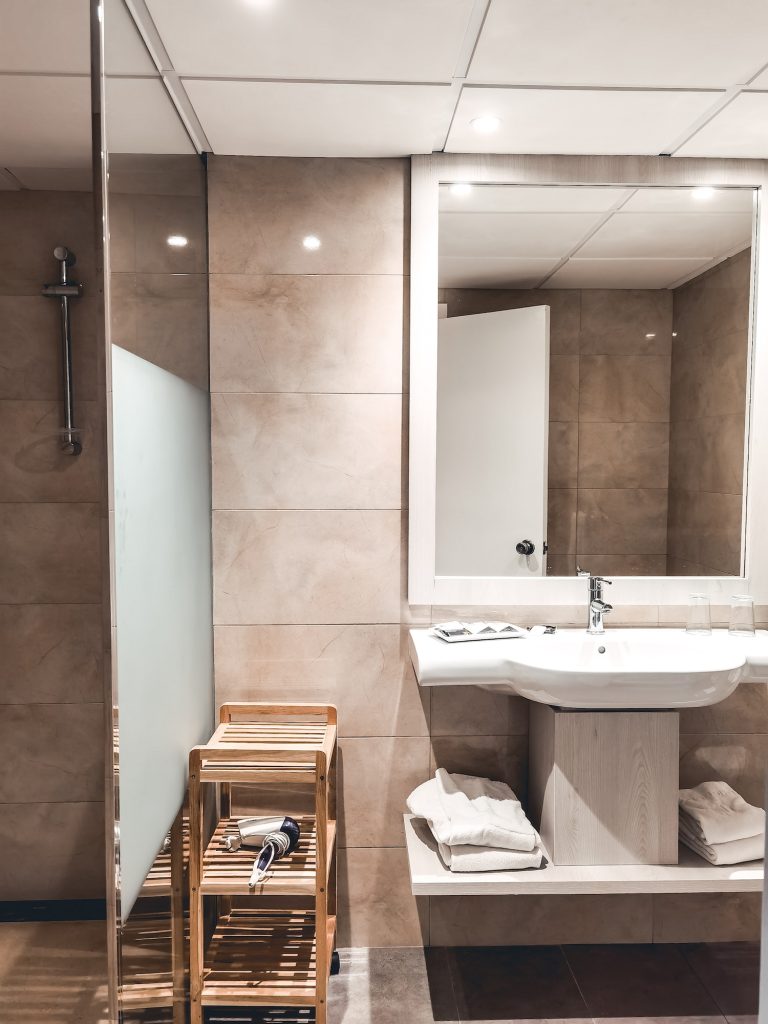 Bathroom in an apartment, sink and mirror, modern interior design, hotel, towels, dryer, shower
